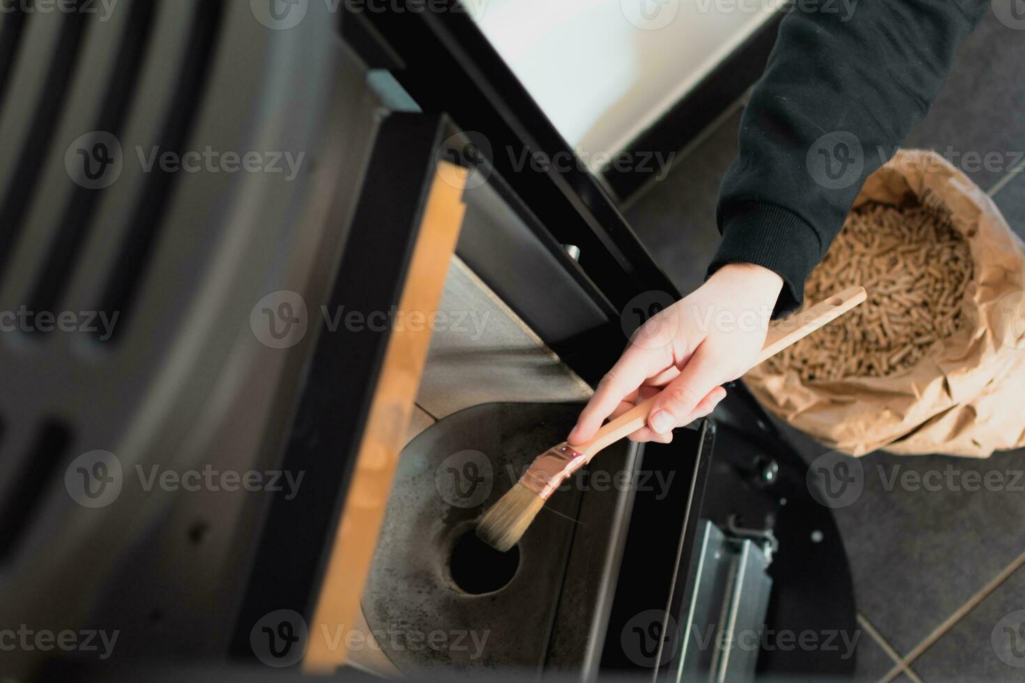 Man cleaning pellet stove with brush photo