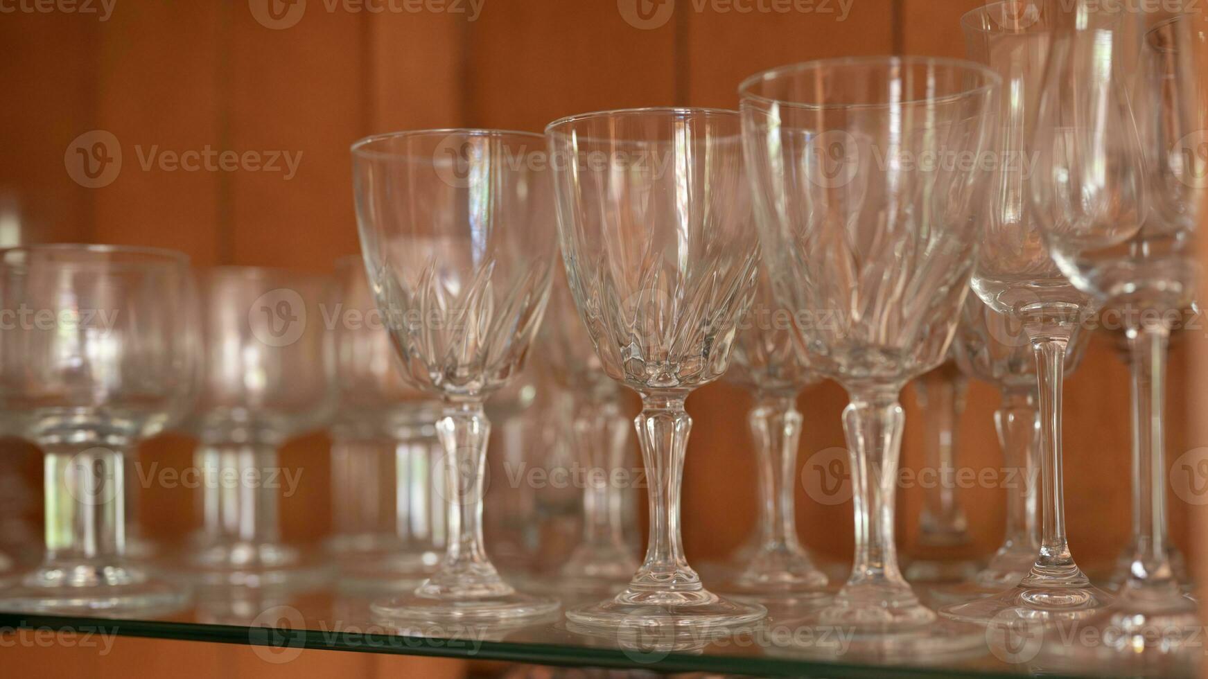 A group of clear drinking glasses on a shelf. photo