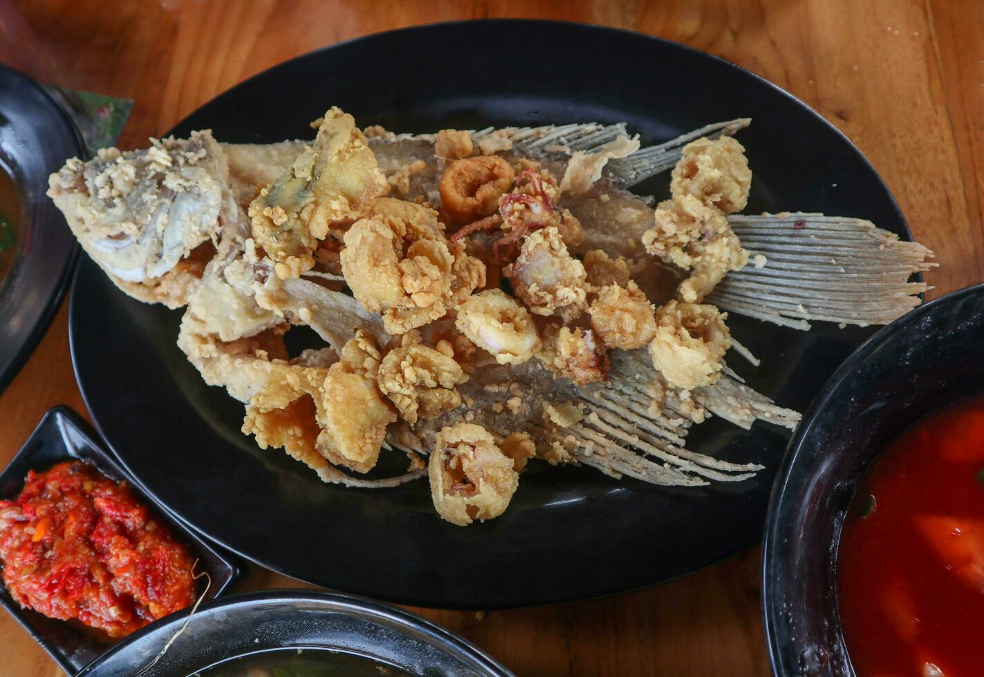 gurame Asam manis o dulce y agrio gurami pescado en harina y profundo frito servido en un de madera mesa foto