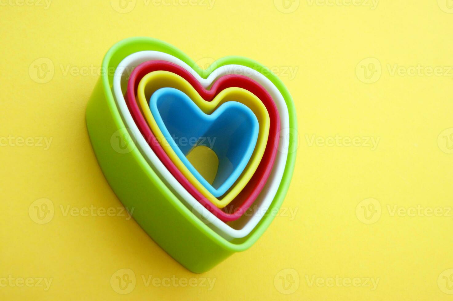 Plastic molds of multi colors for making cookies in the shape of a hearts on a yellow background. photo