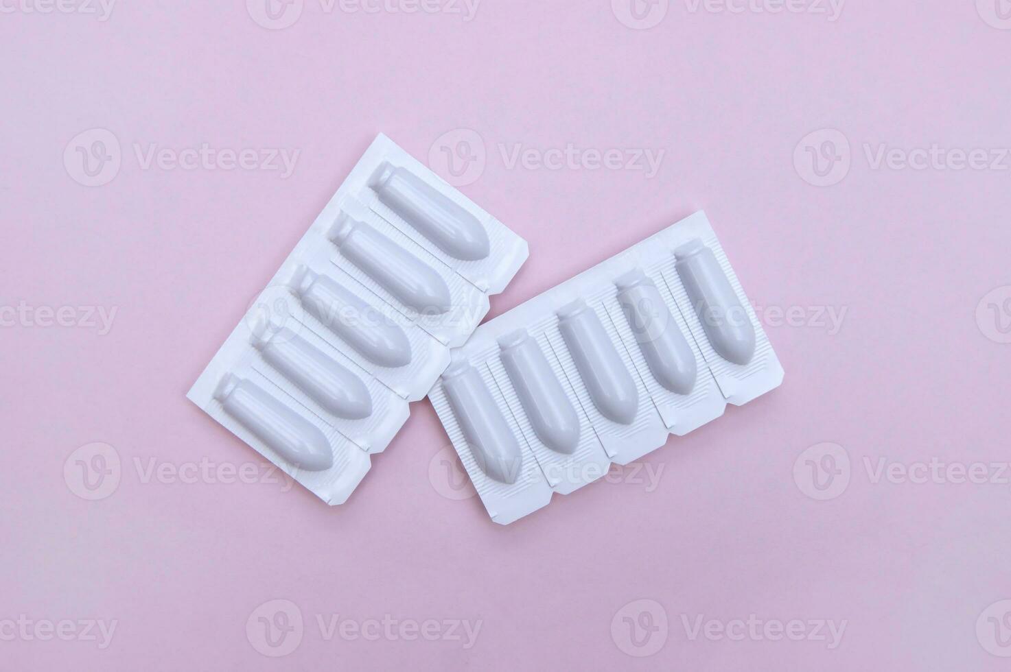 Gynecological medicines for women's health in form of suppository, capsules on pink background. photo