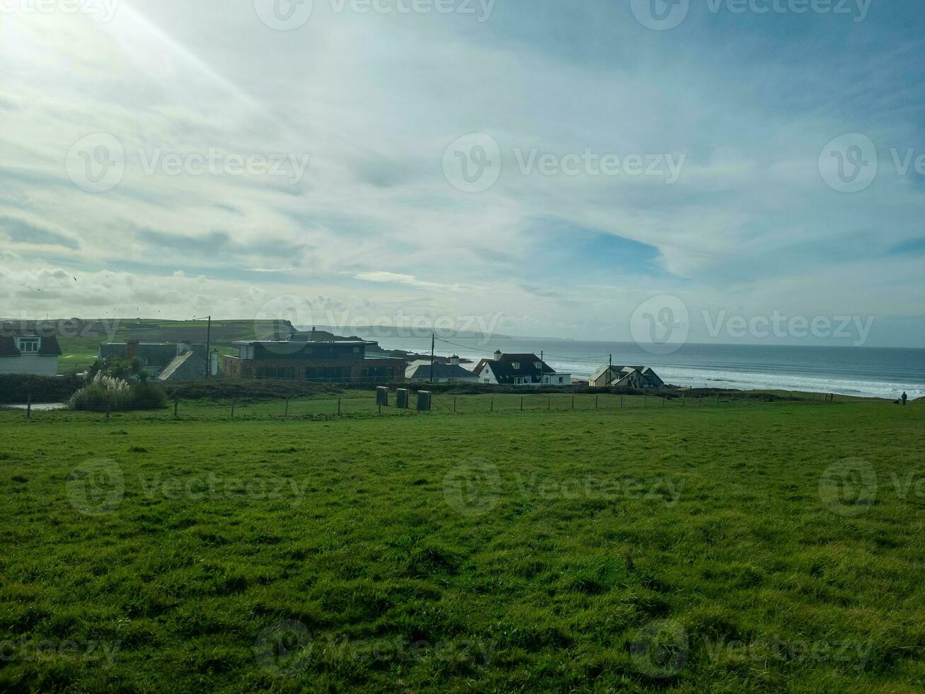 Coastal village with green fields under a cloudy sky. photo