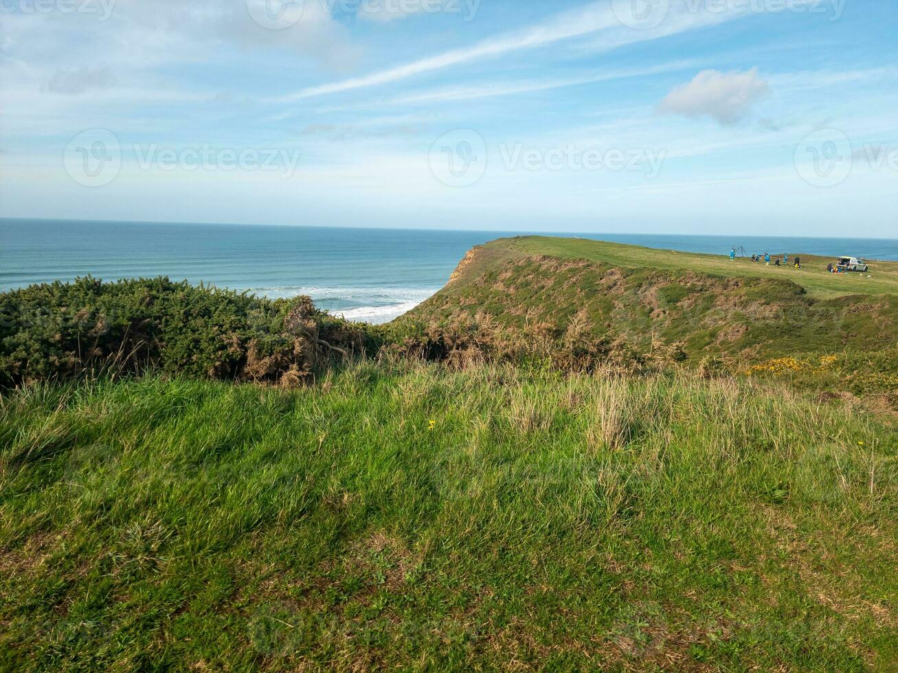 Coastal landscape with green grassy cliff and blue sea under a clear sky. photo
