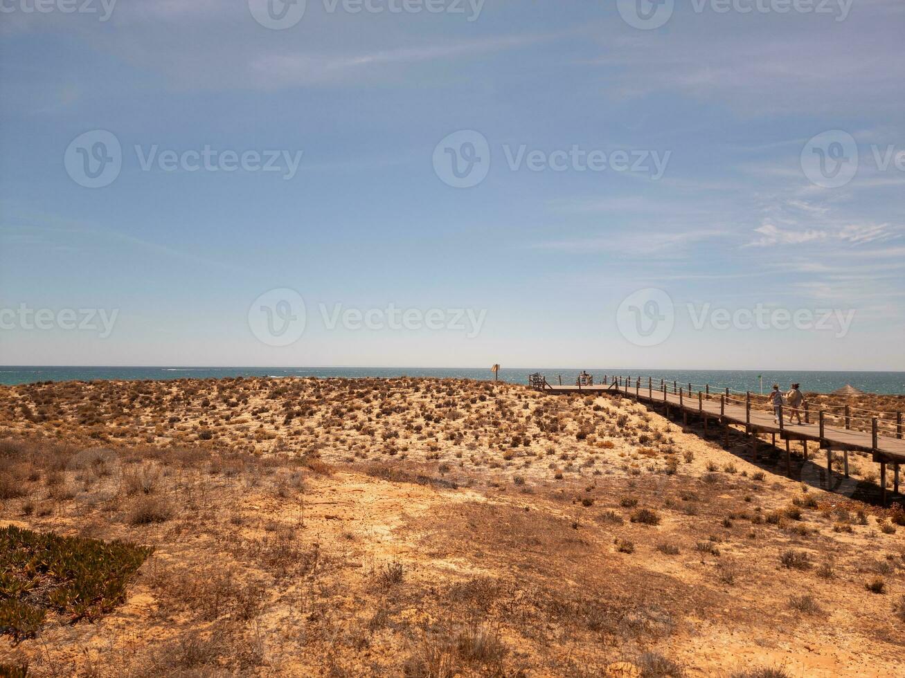 Wooden boardwalk on the beach with a clear blue sky. photo