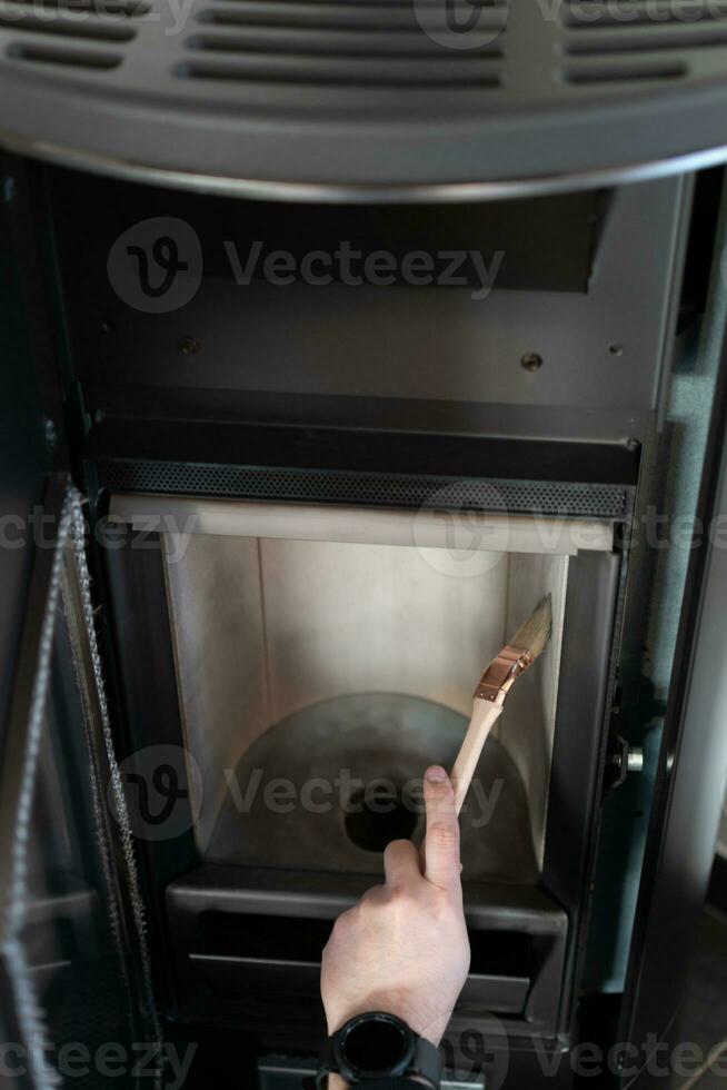 Man cleaning pellet stove with brush photo