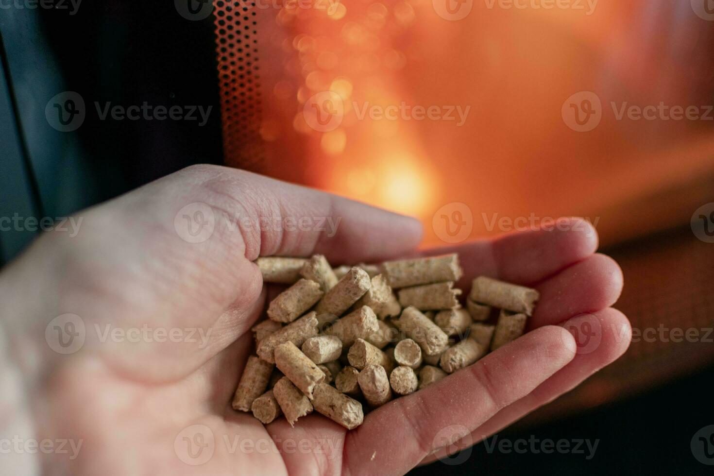 mano participación pellets en frente de el vaso de un estufa con un hermosa fuego foto