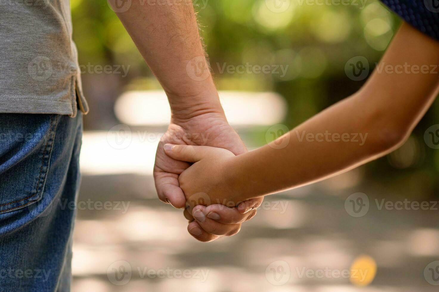 el del padre mano retenida estrechamente el mano de su pequeño hijo en contra el antecedentes de verde follaje, de cerca foto