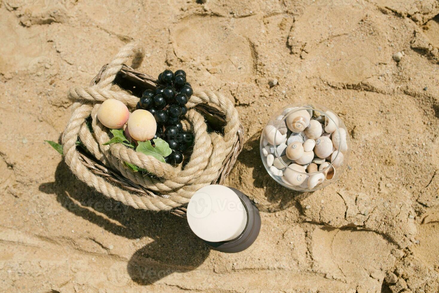 Fruits are in a basket, a candle, sea stones in a glass vase. Decor of a romantic dinner by the sea or ocean photo