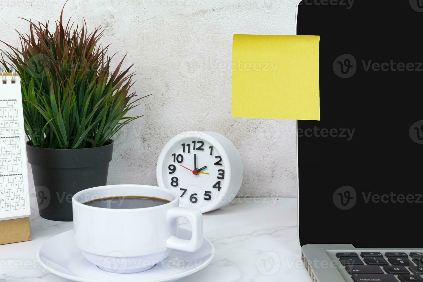 Yellow sticky note on a notebook with coffee, notepad and reading glass. photo