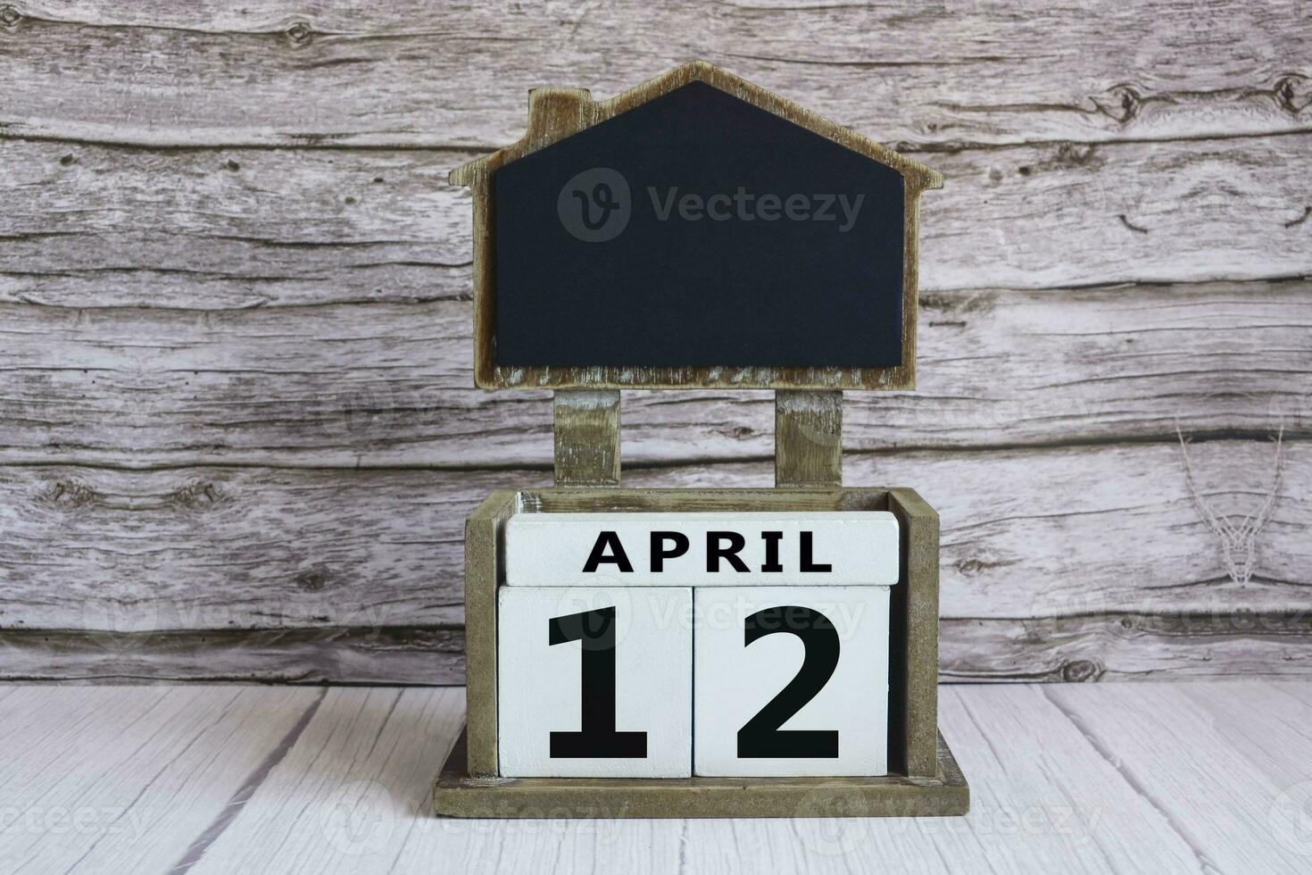Chalkboard with April 12 date on white cube block on wooden table. photo