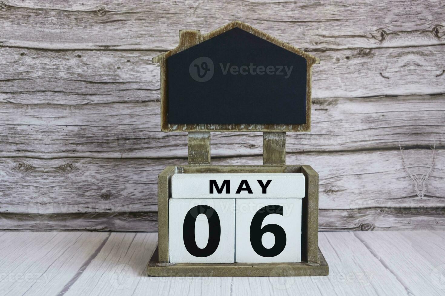 Chalkboard with May 06 date on white cube block on wooden table. photo