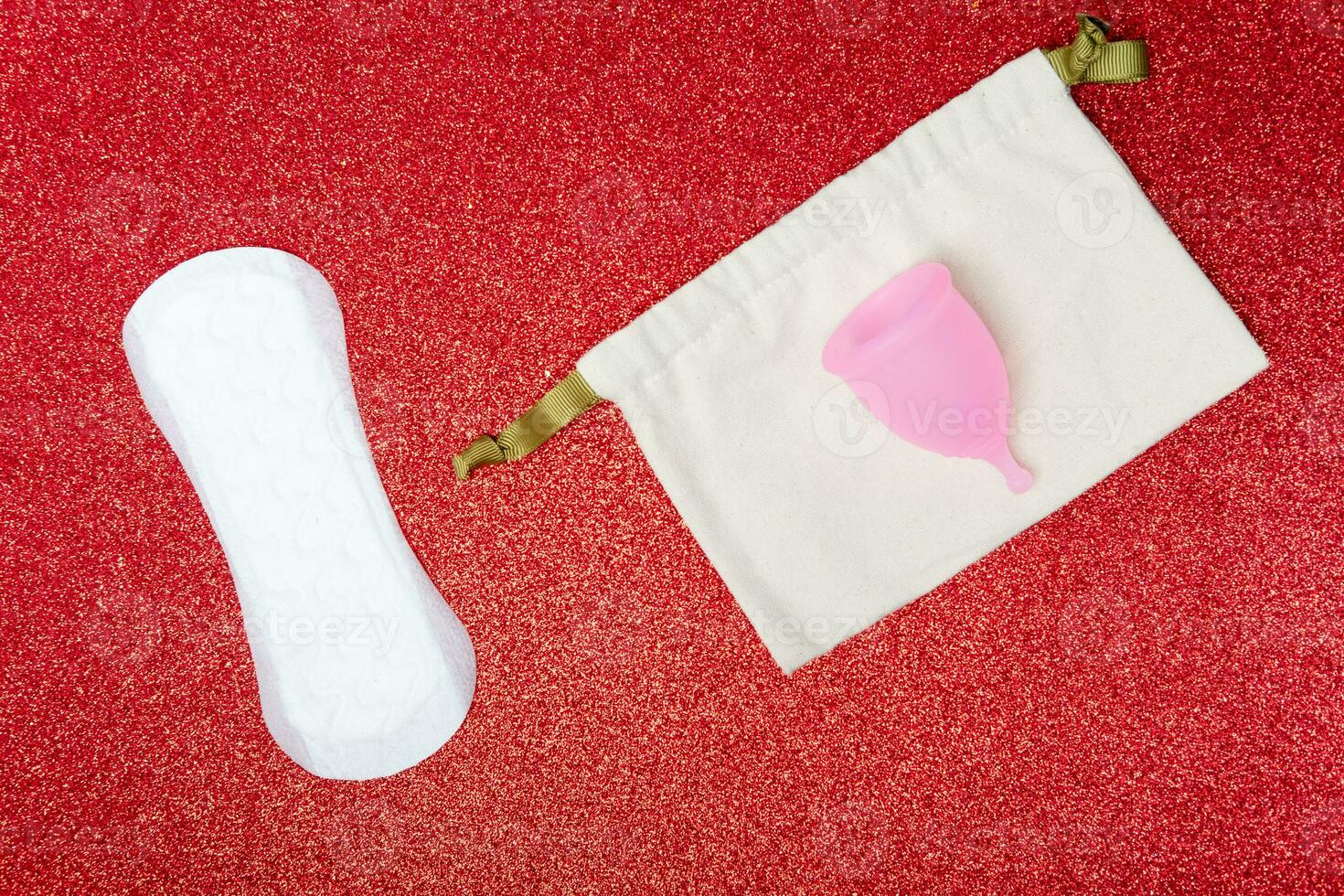 menstrual cup and panty liner on shiny red background,top view. Zero waste concept. Eco-friendly menstrual products photo