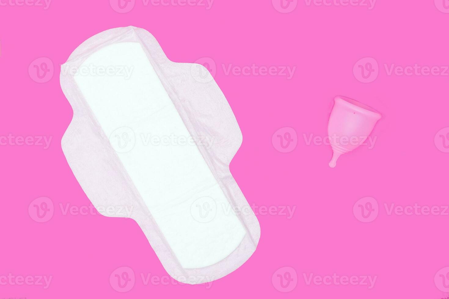 menstrual cup and regular feminine pad on a pink background, top view, copy space. Zero waste concept. Eco-friendly menstrual products photo