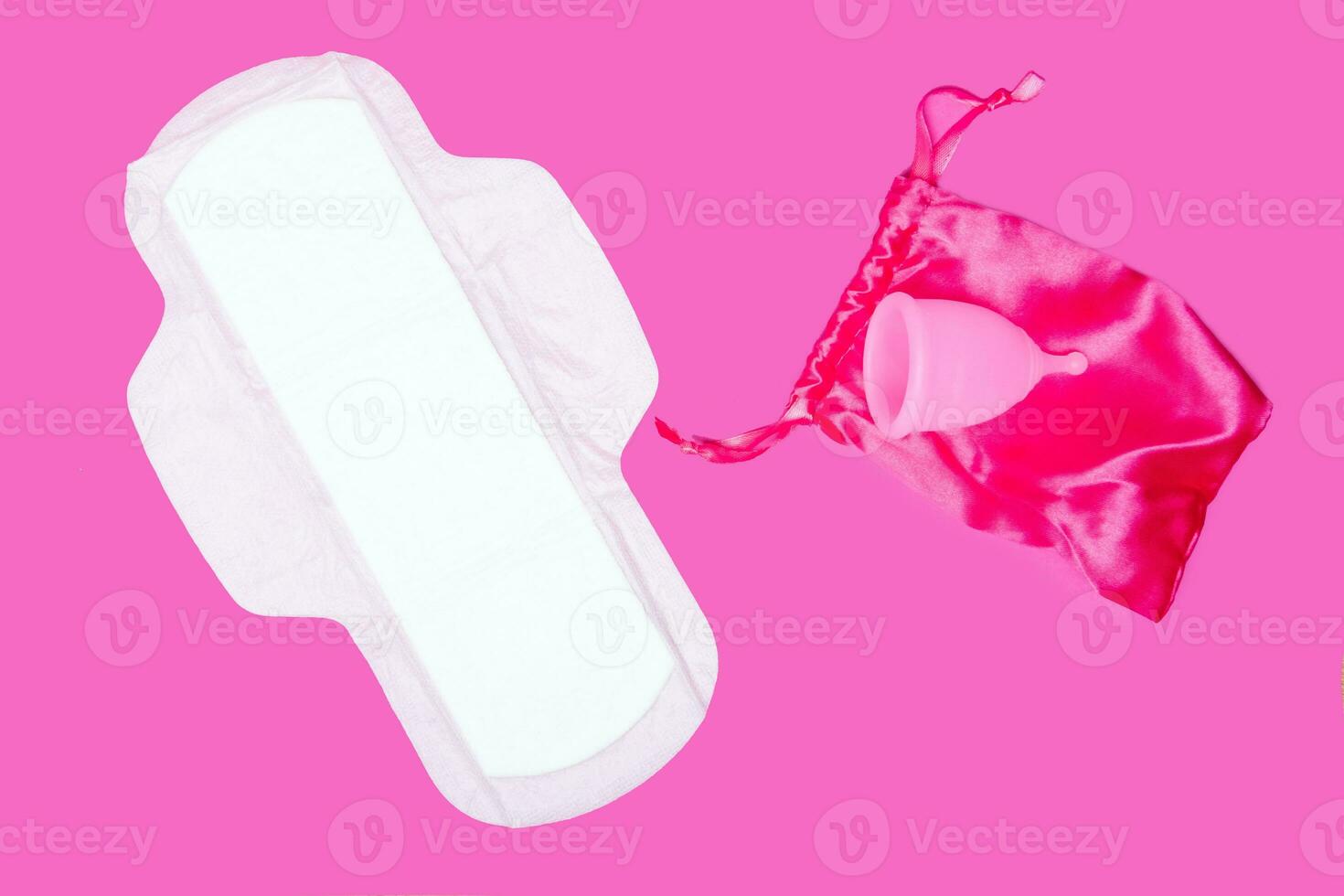 menstrual cup and regular feminine pad on a pink background, top view, copy space. Zero waste concept. Eco-friendly menstrual products photo