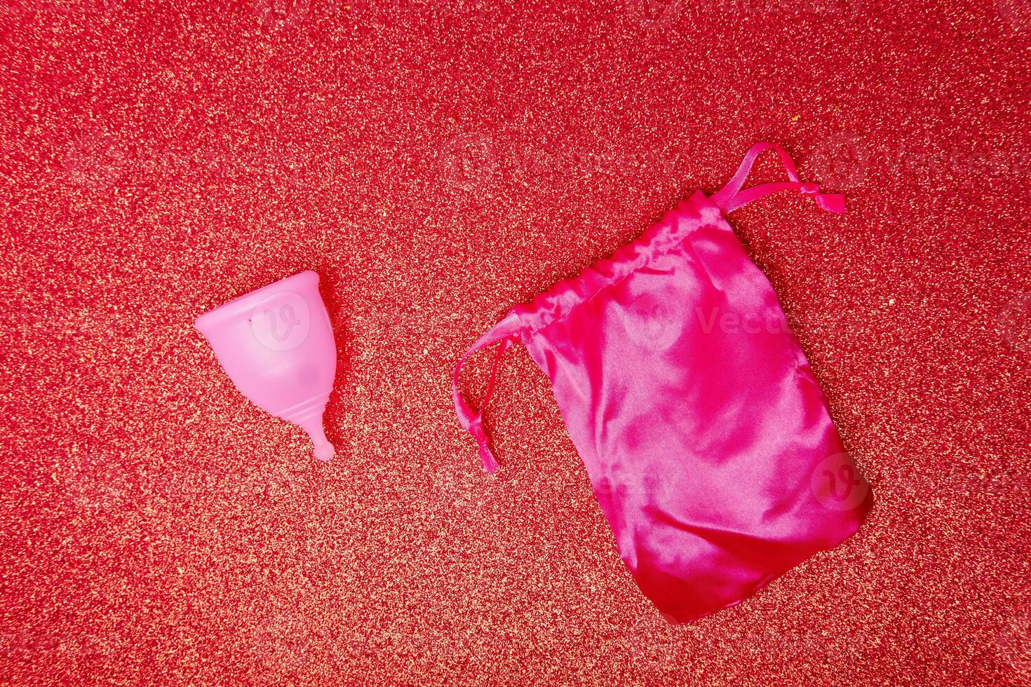 menstrual cup with satin pouch on shiny red background, top view. Zero waste concept. Eco-friendly menstrual products photo