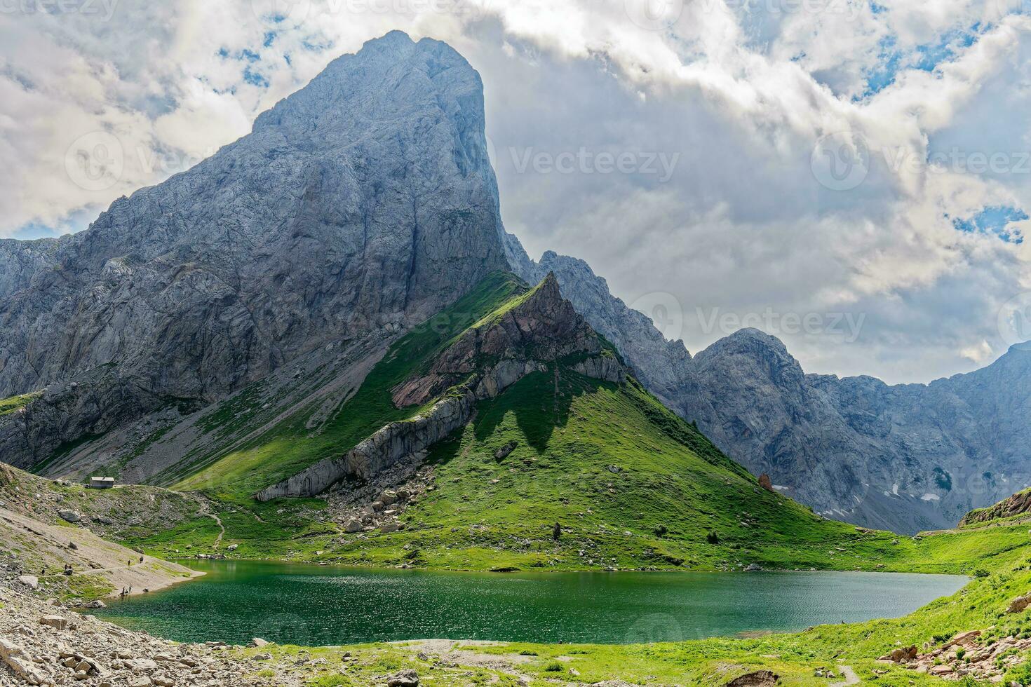 View of Volaia Lake, Wolayersee, in the border of Italy and Austria with Coglians mountain in the background. Cloudy day with some sun opening. Vibrant colors. Beautiful destinations for hikers. photo