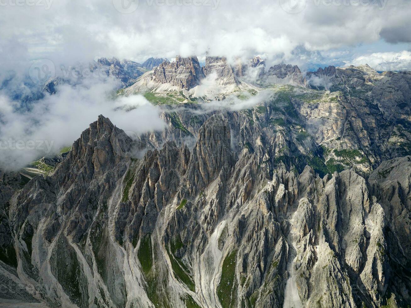 Aerial view of Cadini di Misurina mountains with Tre Cime di Lavaredo mountains in the background during a sunny day with some clouds. Dolomites, Italy. Dramatic and cinematic landscape. photo