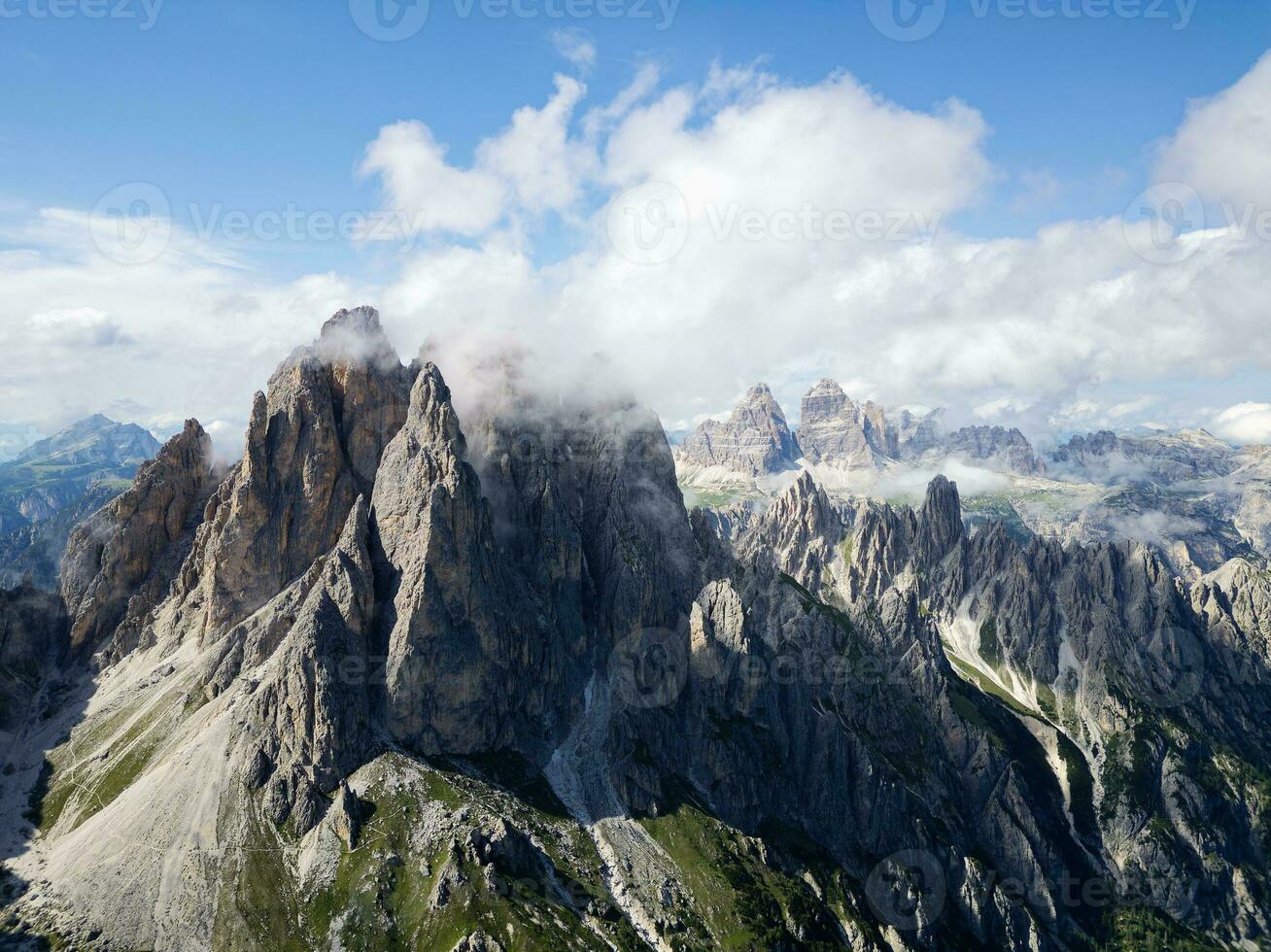 Aerial view of Cadini di Misurina mountains with Tre Cime di Lavaredo mountains in the background during a sunny day with some clouds. Dolomites, Italy. Dramatic and cinematic landscape. photo