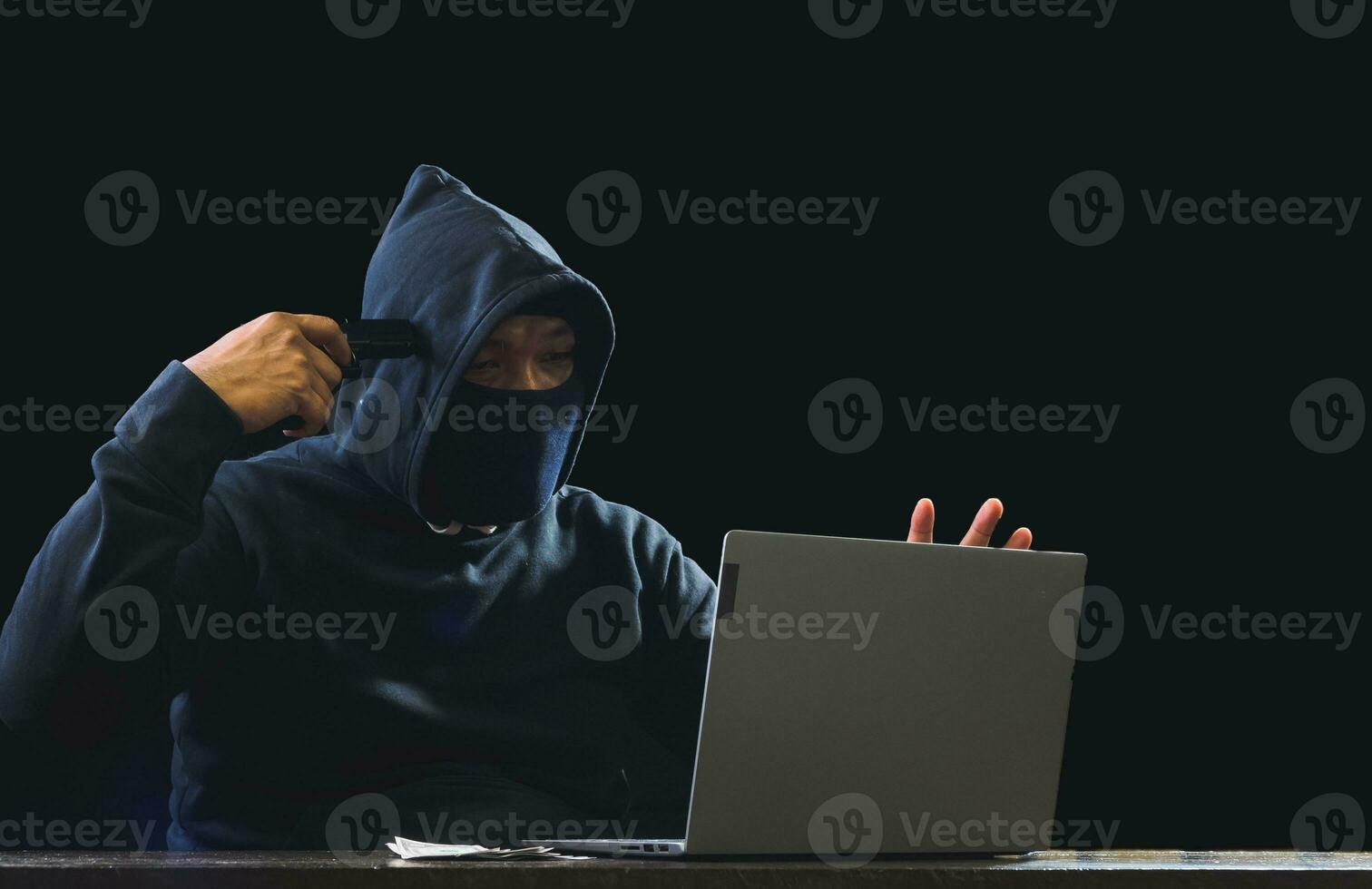 Portrait hacker spy man one person in black hoodie sitting on table looking computer laptop used login password attack security to data digital internet network system night dark background copy space photo