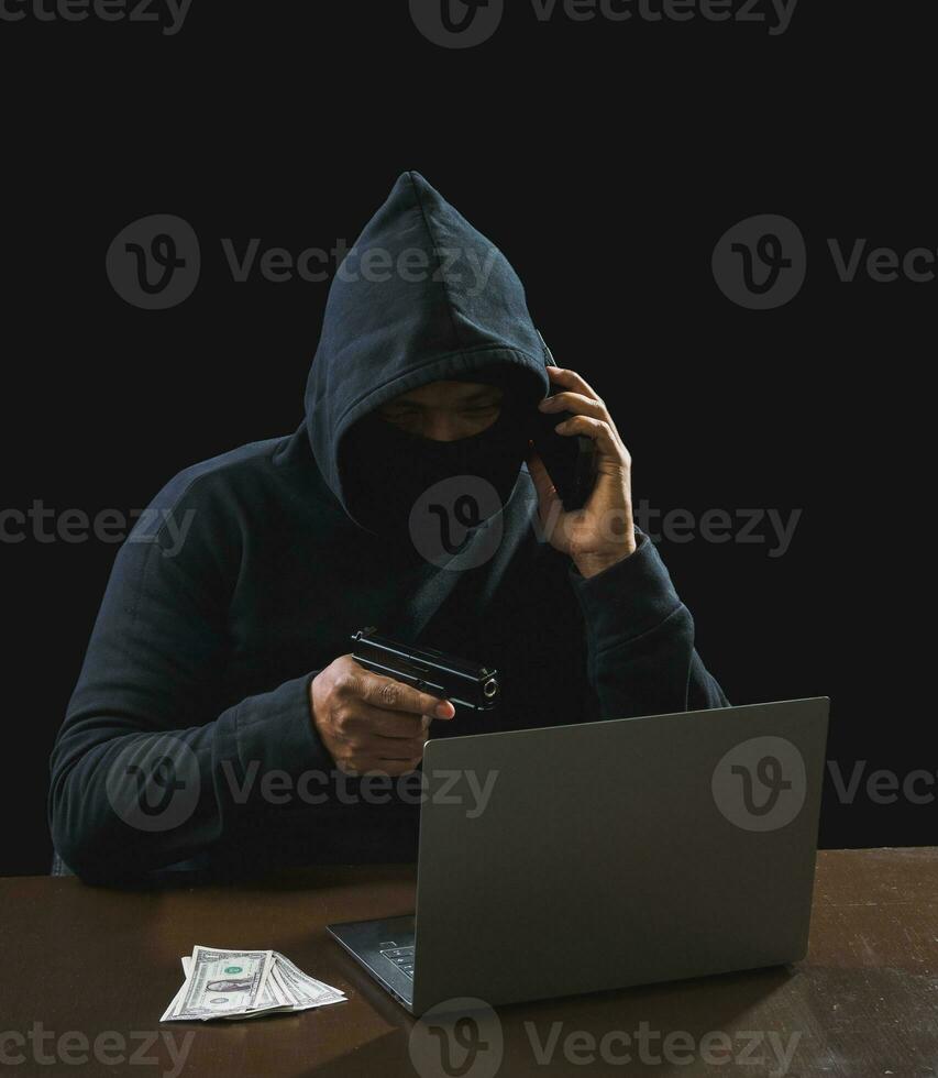 Portrait hacker spy man one person in black hoodie sitting on table looking computer laptop used login password attack security to data digital internet network system night dark background copy space photo