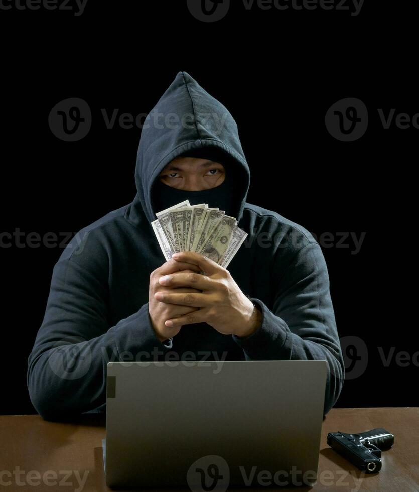 Portrait hacker spy man one person in black hoodie sitting on table looking computer laptop used login password attack security to data digital internet network system night dark background copy space photo