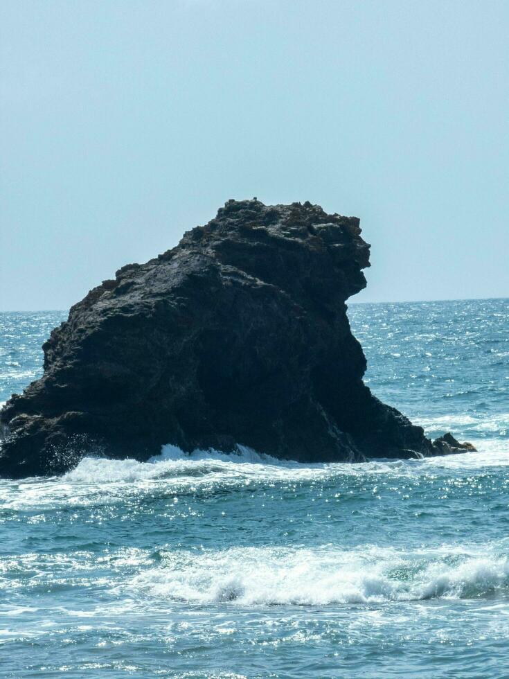 Isolated rock formation in the sea under blue sky. photo