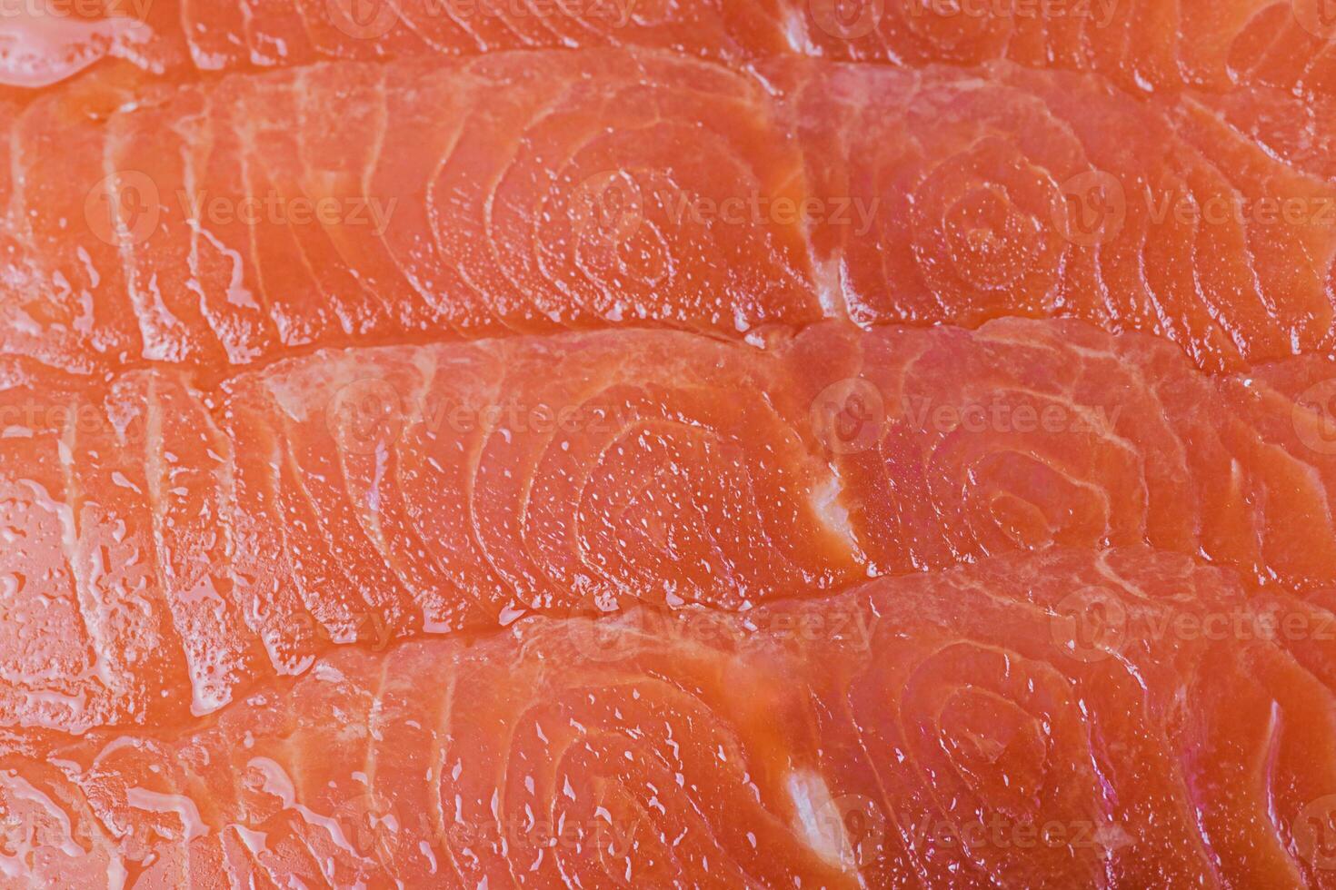 Lightly salted salmon fillet cut into thin pieces. Red fish macro photo as background.