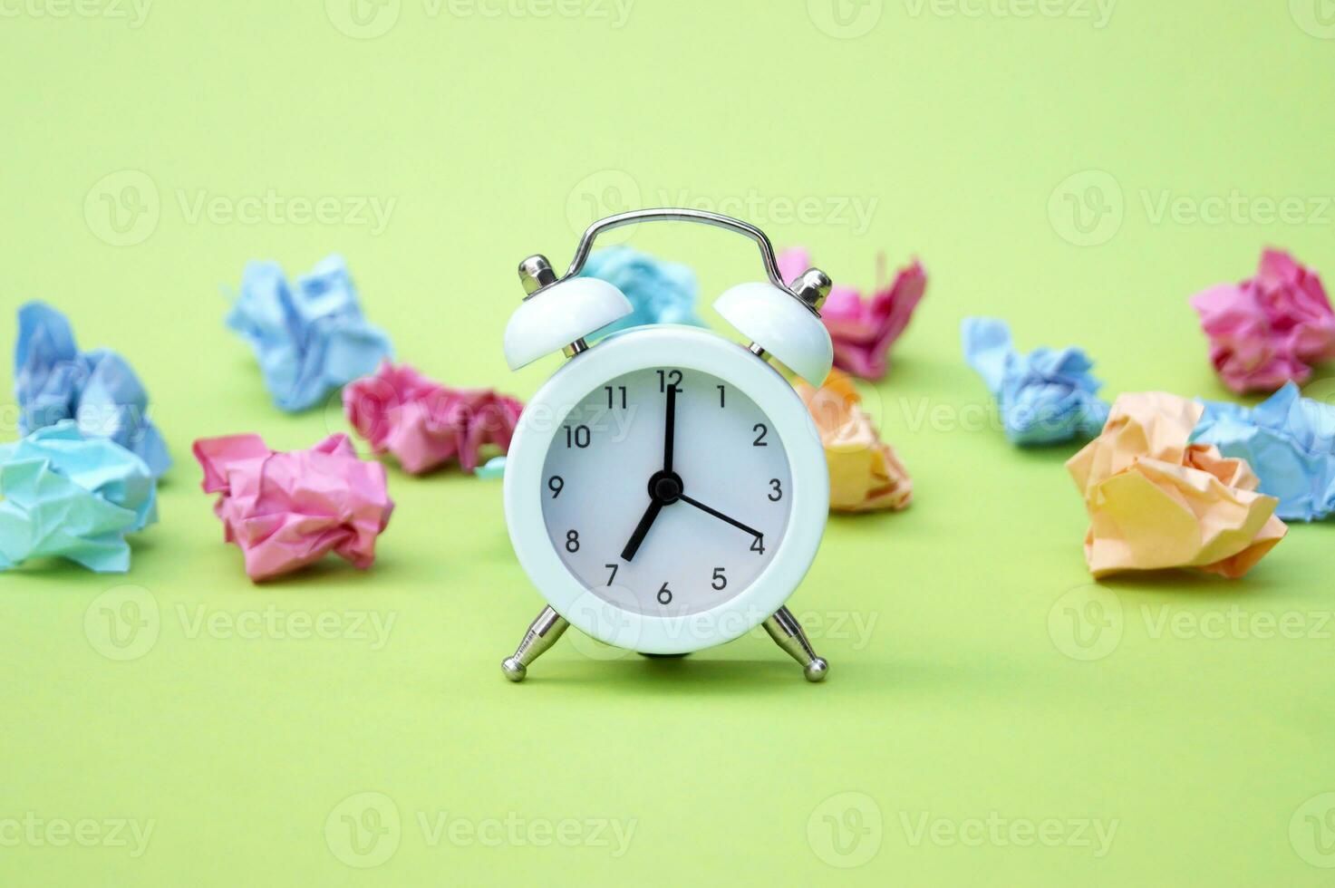 Vintage white alarm clock on a background of crumpled multicolored stickers. photo