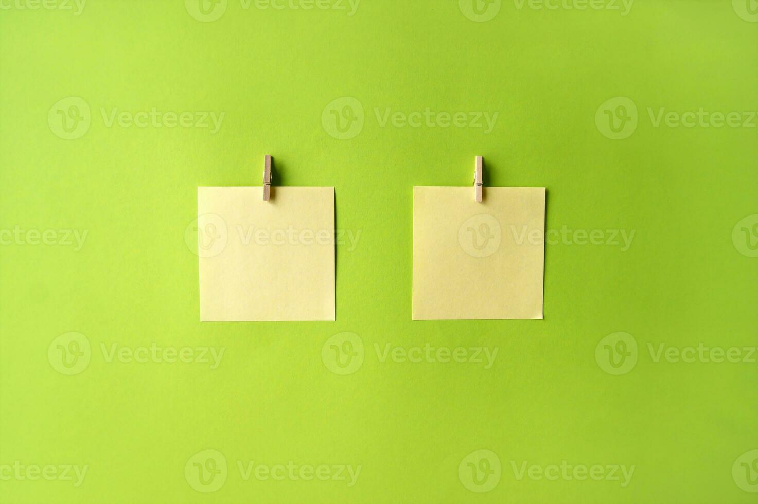 Two yellow sticker with blank space for an inscription or a reminder on a green background, attached to a clothespin. photo