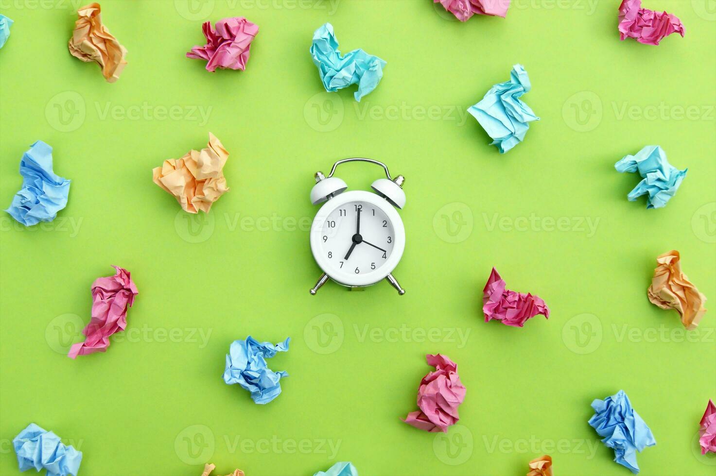 Vintage white alarm clock on a background of crumpled multicolored stickers. photo