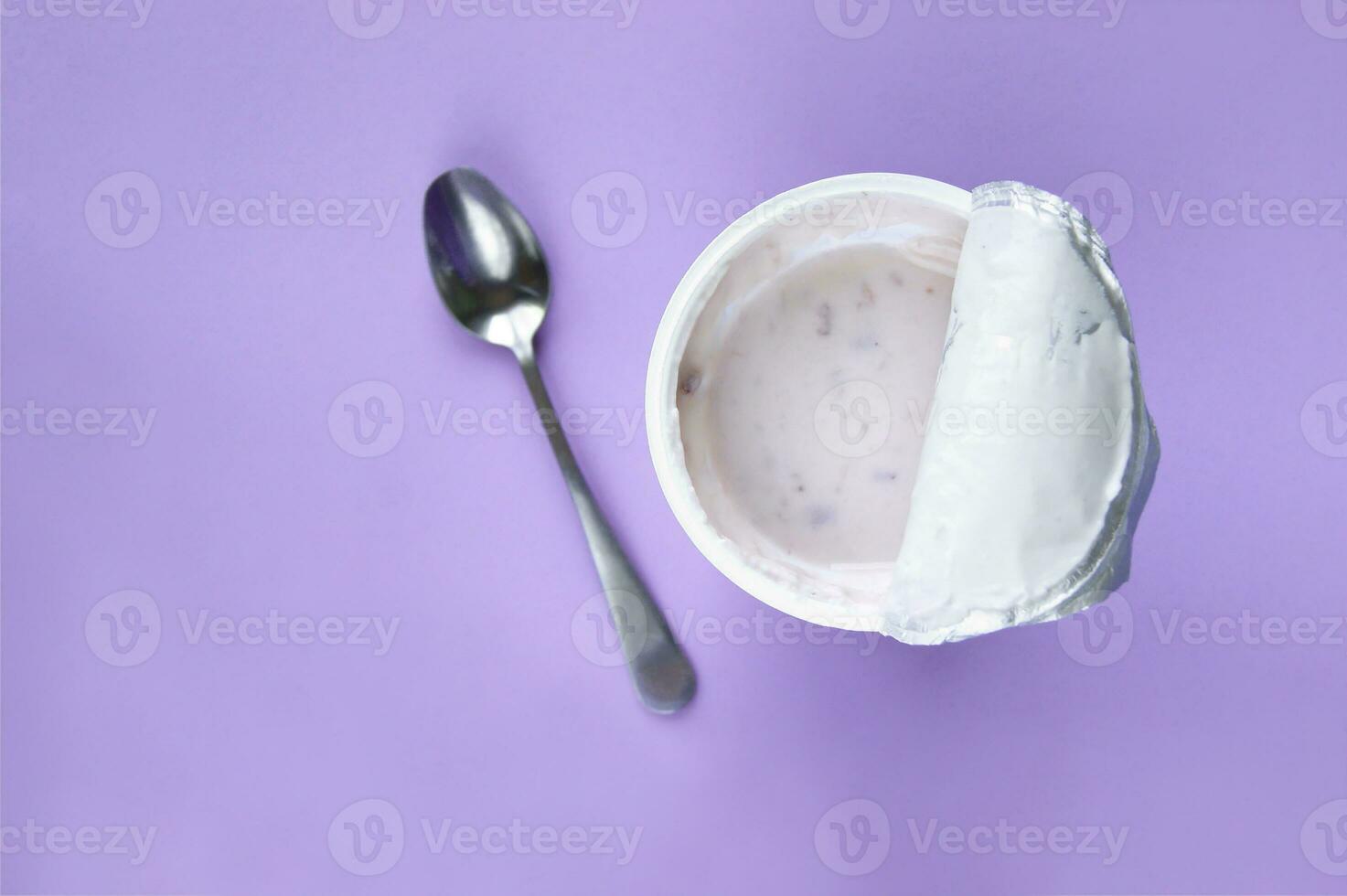 A pink yogurt with strawberry in an open plastic cup on pink background. photo