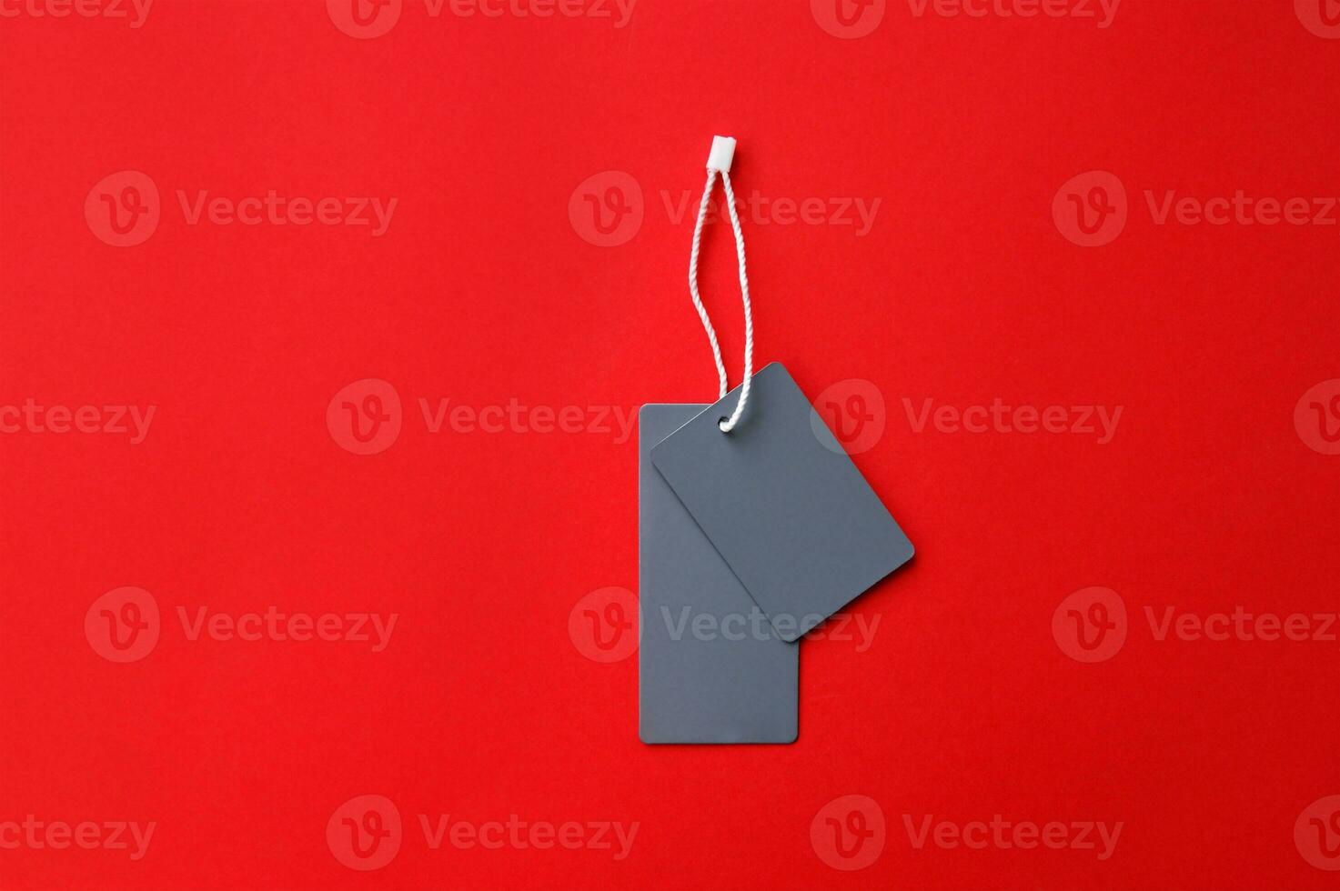 Two empty gray tags on a red background. Copy photo