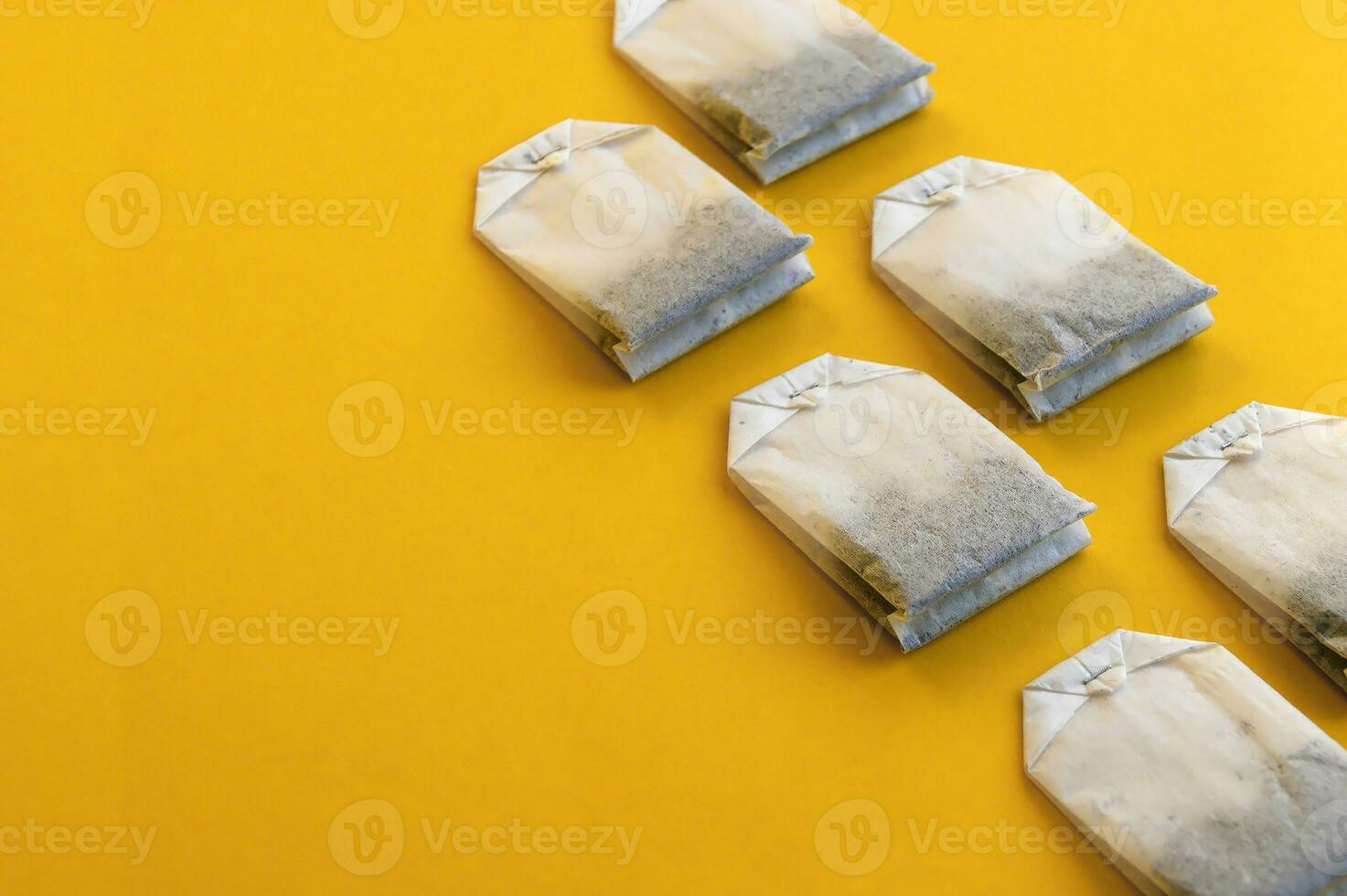 A lot of disposable tea bags on a yellow background. photo