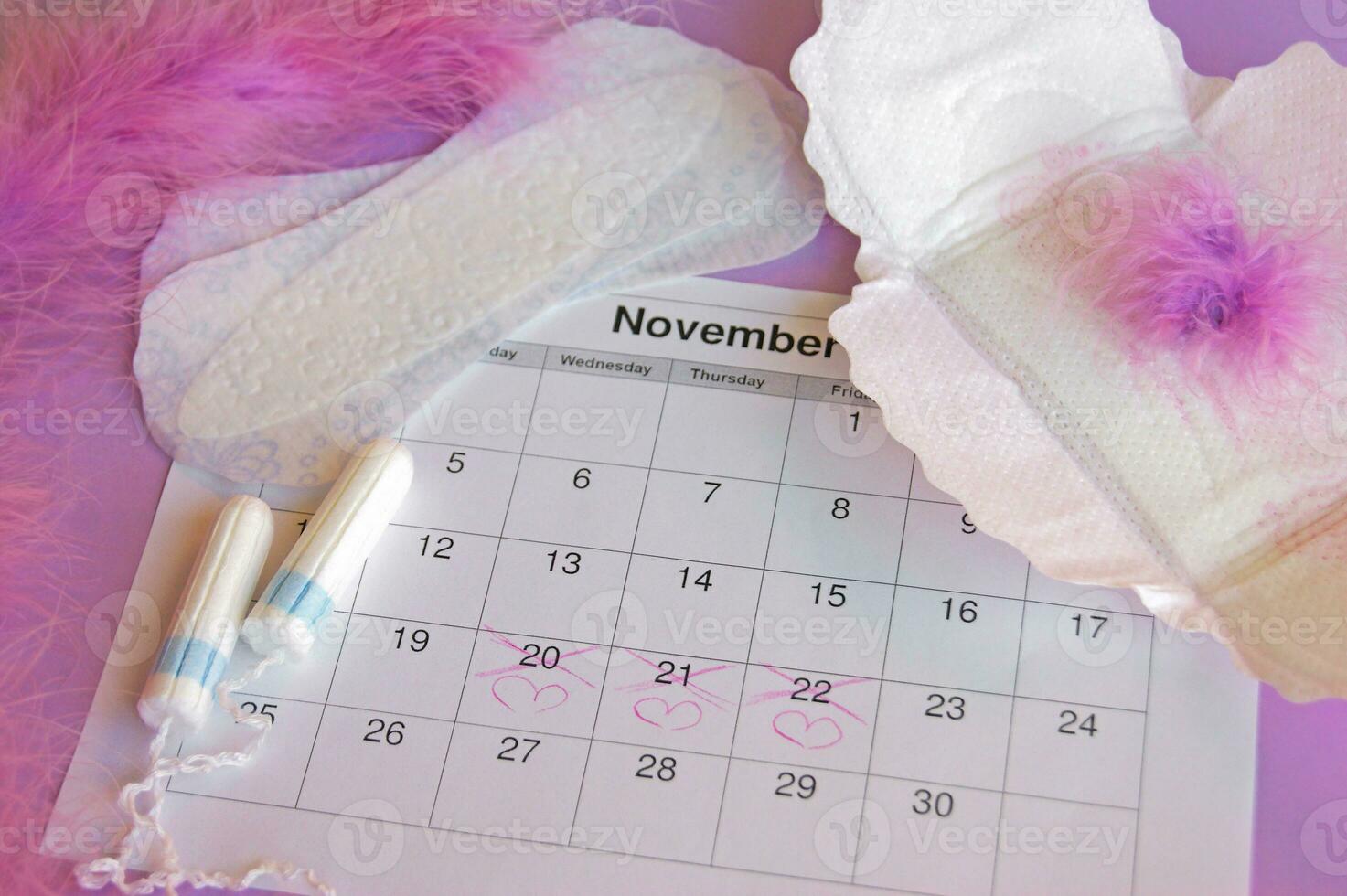 Menstrual pads and tampons on menstruation period calendar with on red background. photo