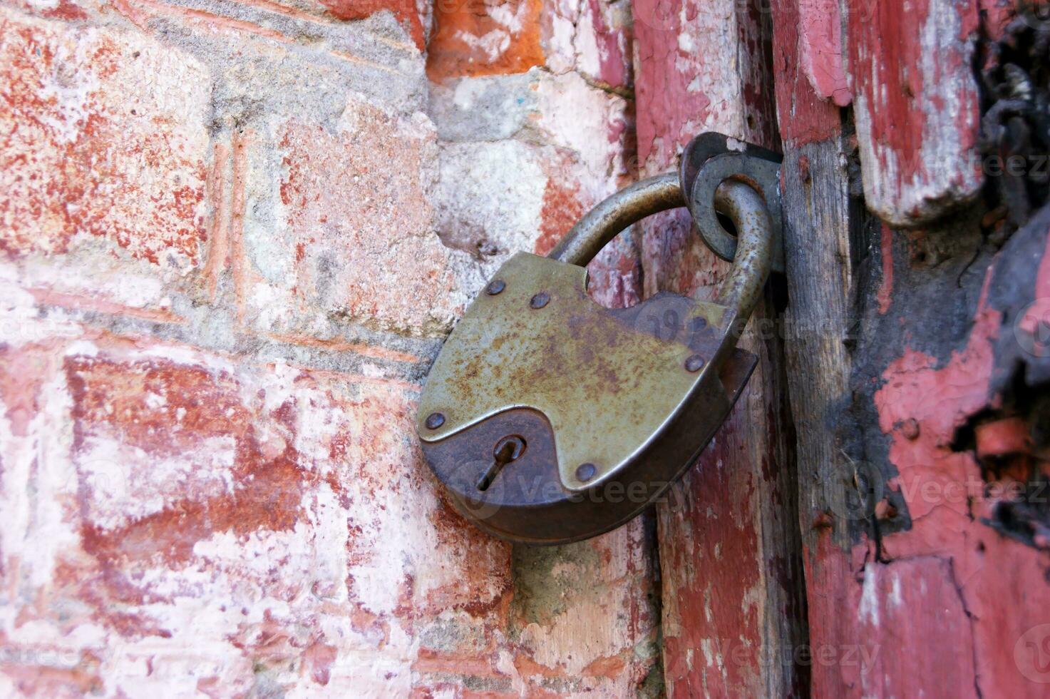 An old padlock on closed doors, a rusty lock on the gate. photo