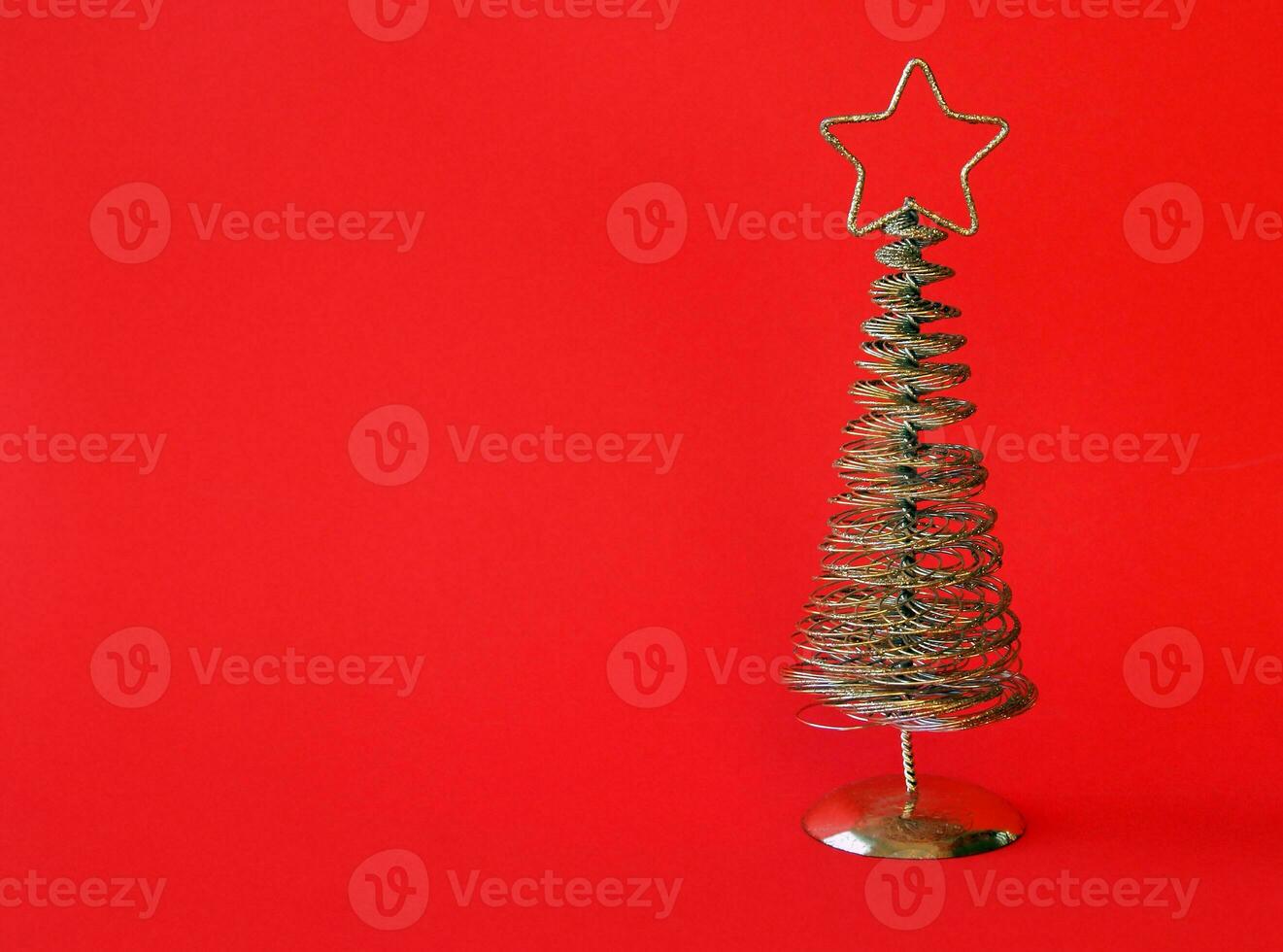 dorado metal Navidad árbol con un estrella en arriba, rojo antecedentes. foto