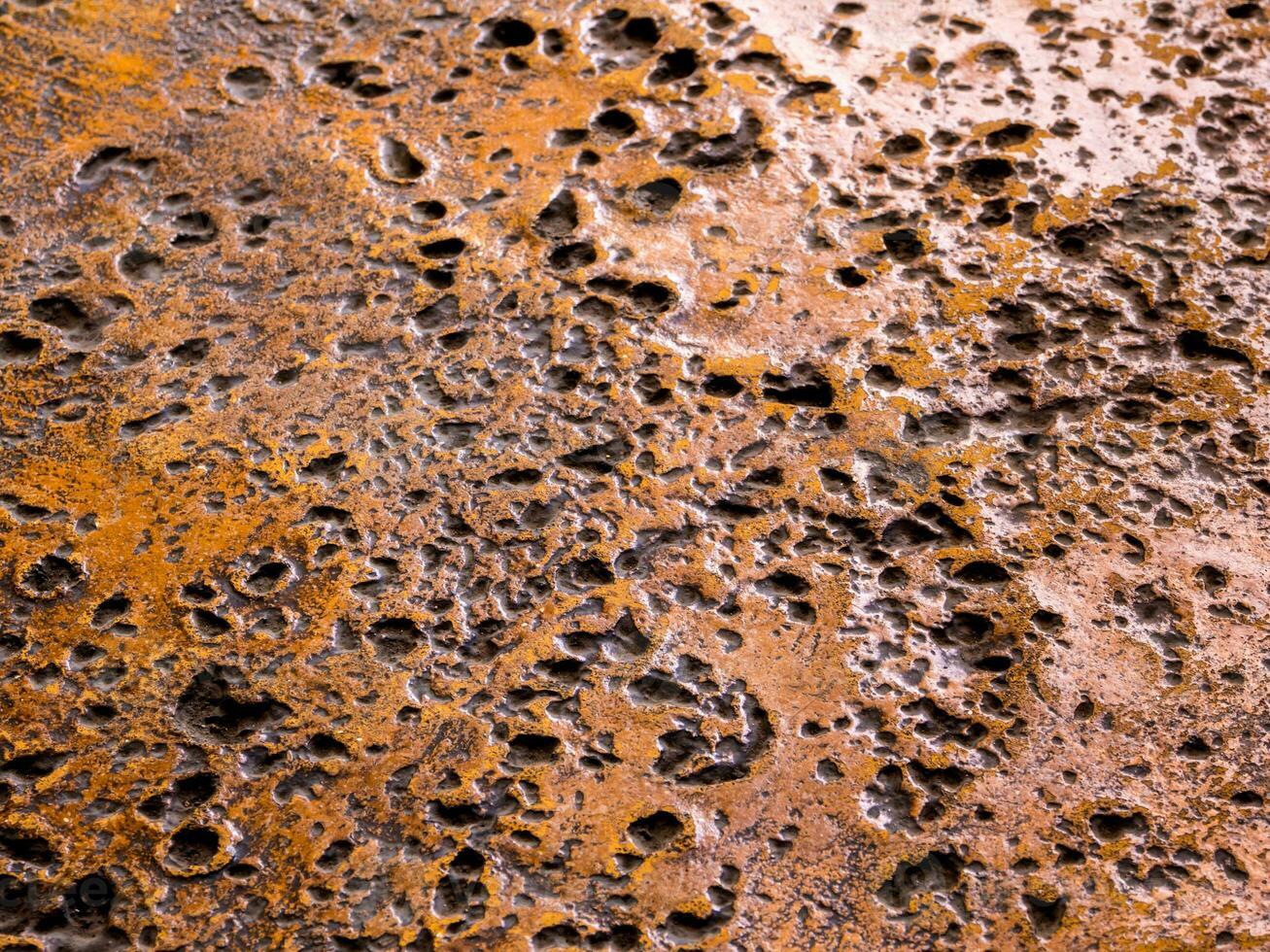 Many rugged holes on the rusty color concrete floor photo