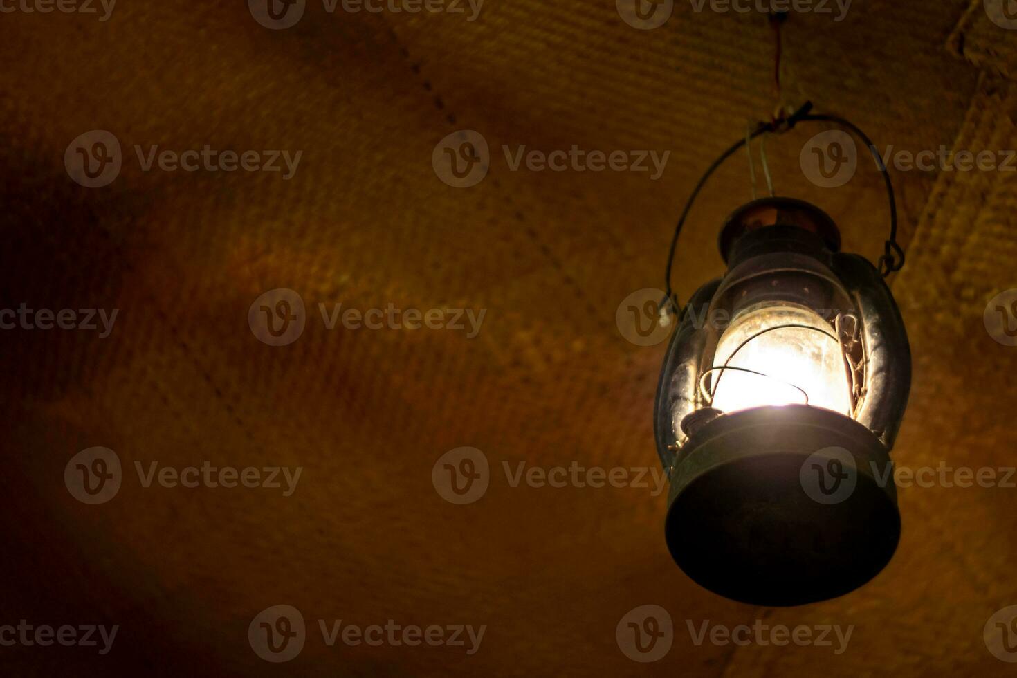 Bright light in an ancient lantern hanging in an old room photo