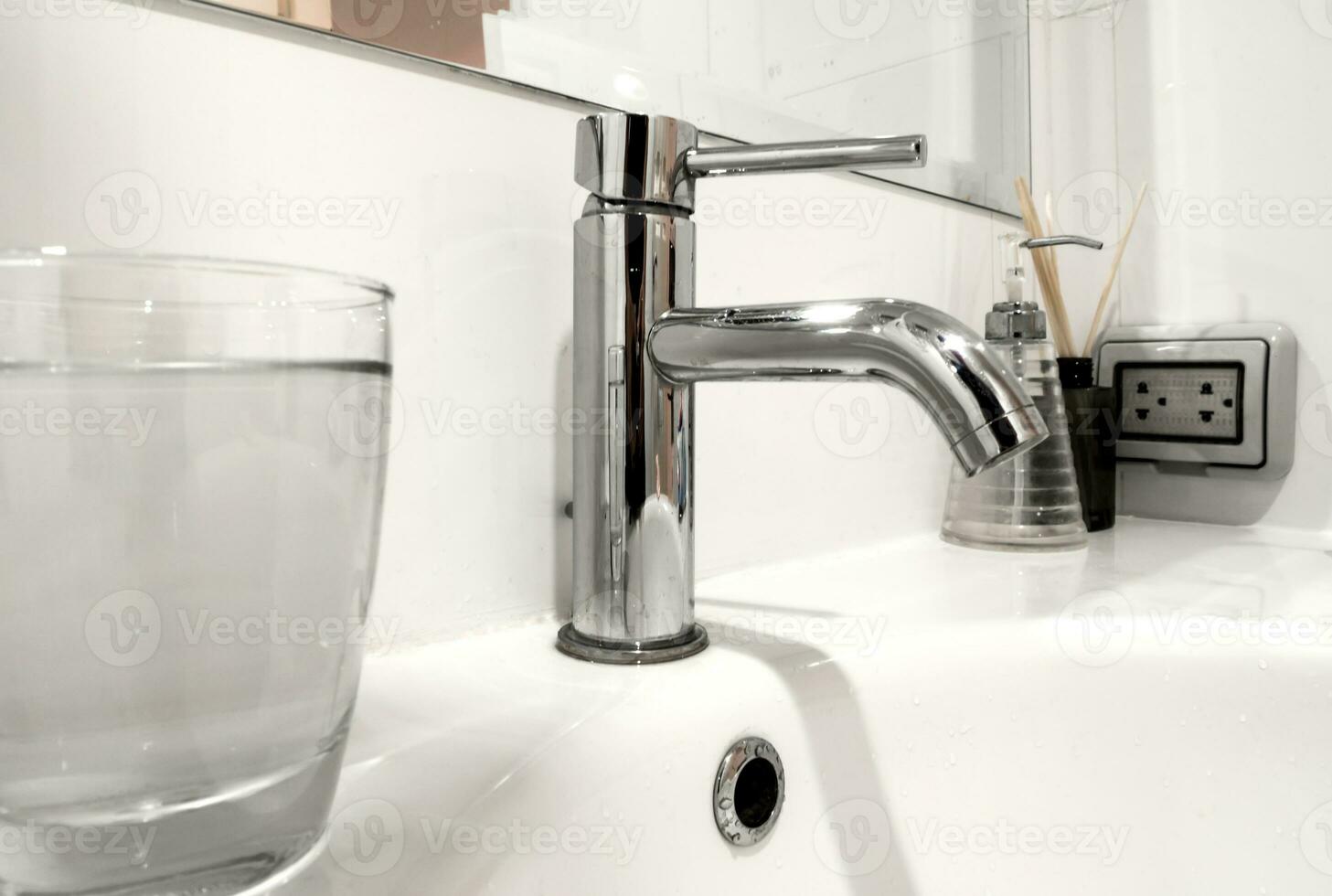 Bathroom faucet and wash basin with water glass photo