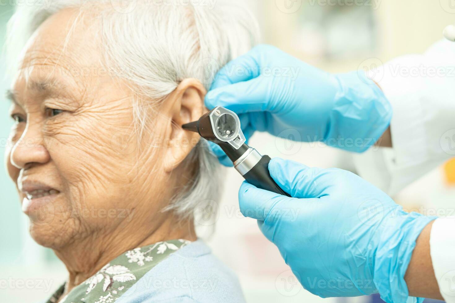 Audiologist or ENT doctor use otoscope checking ear of asian senior woman patient treating hearing loss problem. photo