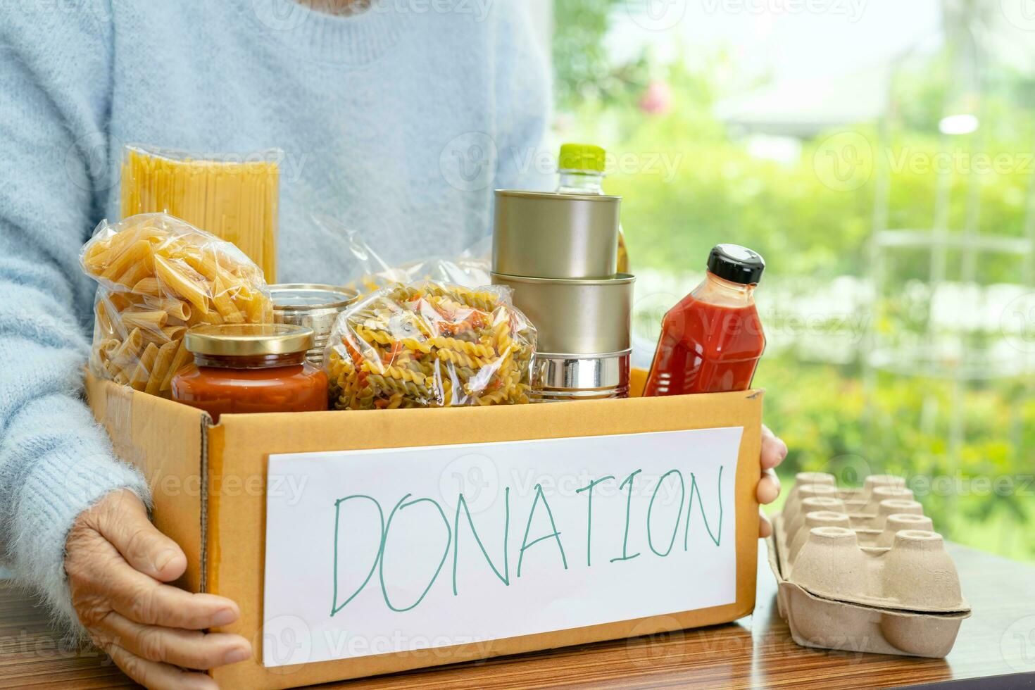 Volunteers putting various dry food in donation box for help people. photo