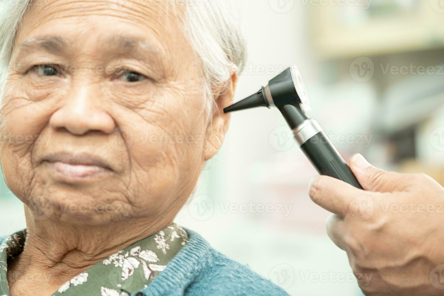 audiólogo o ent médico utilizar otoscopio comprobación oído de asiático mayor mujer paciente tratando escuchando pérdida problema. foto