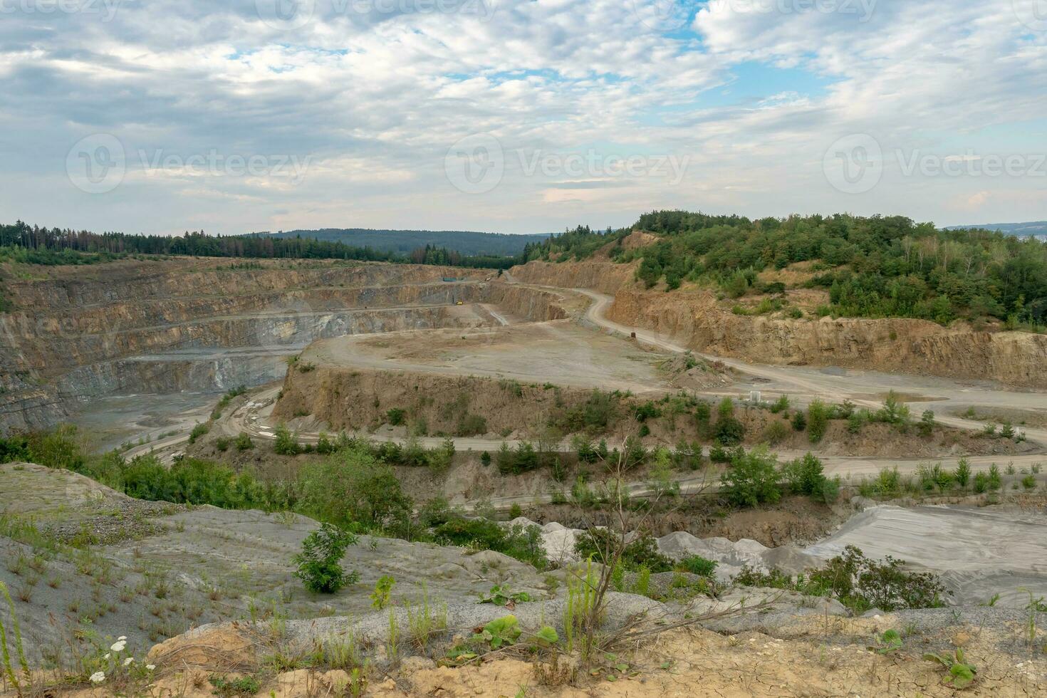 Opencast mining quarry with machinery. Quarrying of stones for construction works. Mining industry in quarry. photo