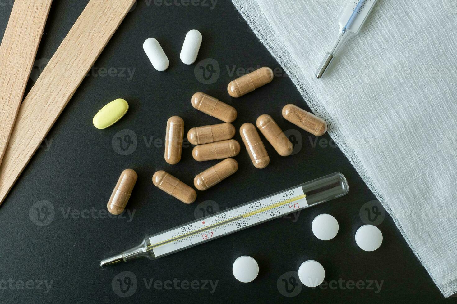 Traditional medical thermometer for measuring body temperature. Pills and medicaments on background. High body temperature. photo