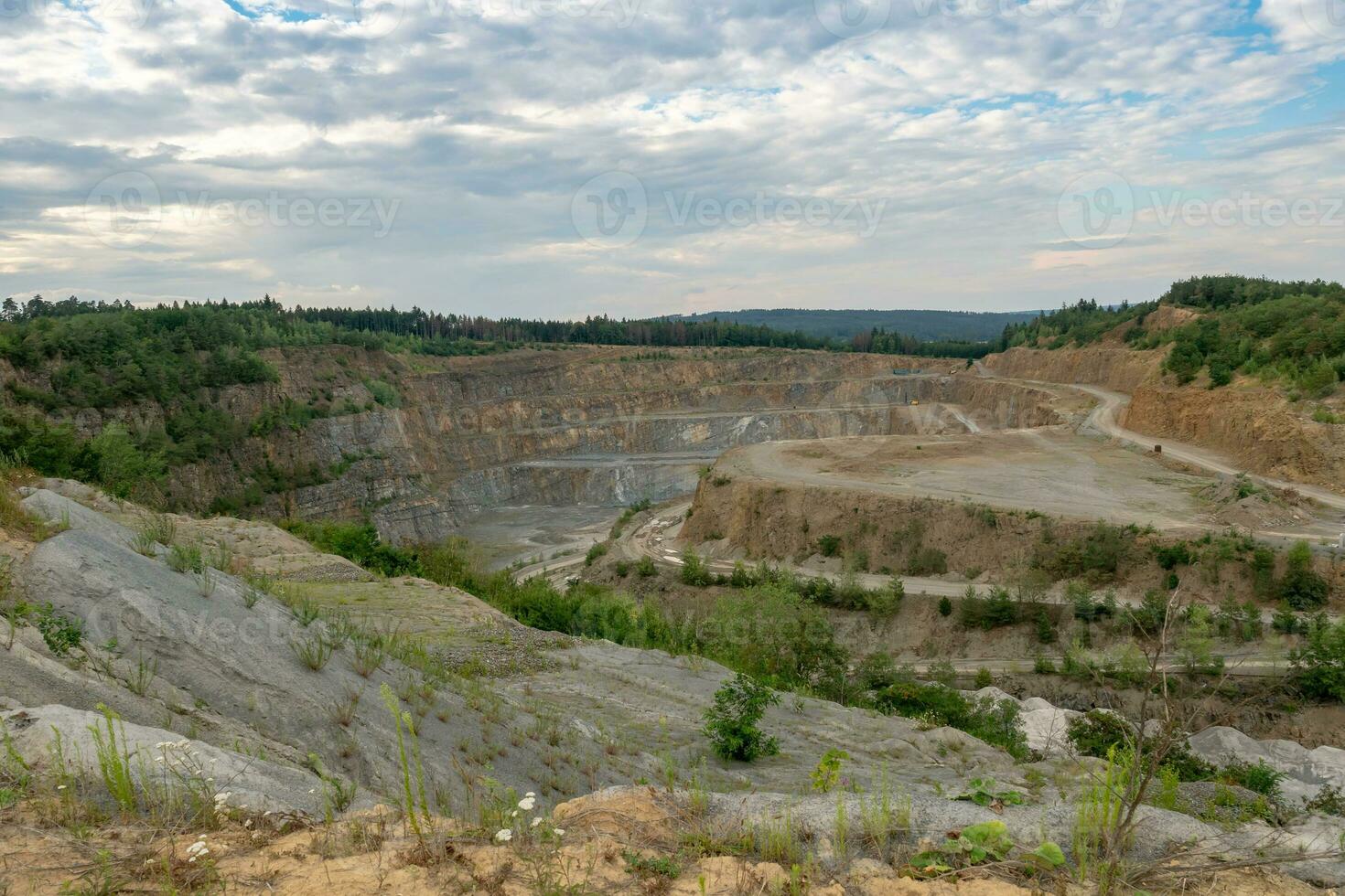 Opencast mining quarry with machinery. Quarrying of stones for construction works. Mining industry in quarry. photo
