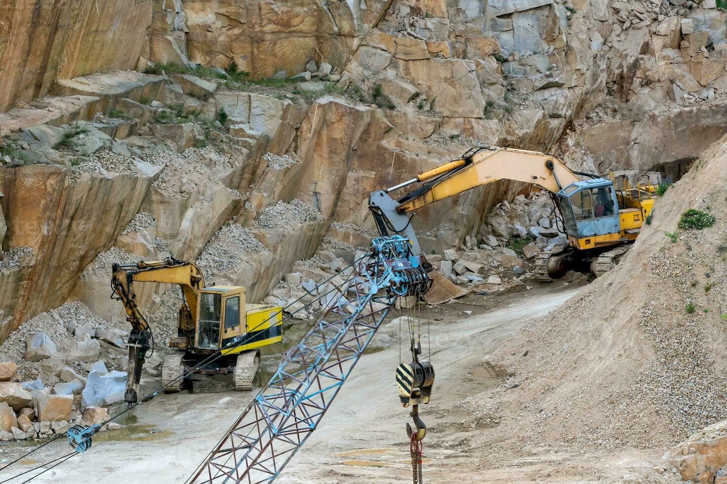 Mining in the granite quarry. Working mining machine - old crane and digger. Mining industry. photo