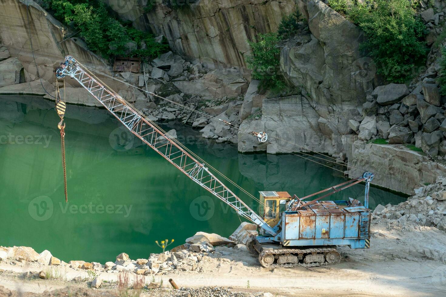 Mining in the granite quarry. Working mining machine - old crane. Mining industry. photo