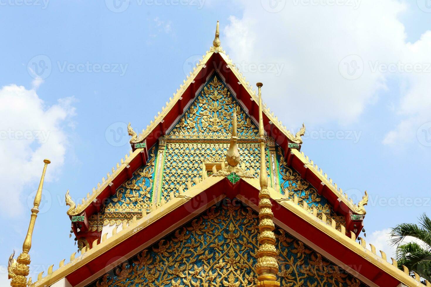 Double isosceles triangle shape gable and roof of Buddhism church and blue sky background, Thailand. Thai native traditional art decorate on gable in golden, blue, red color. photo