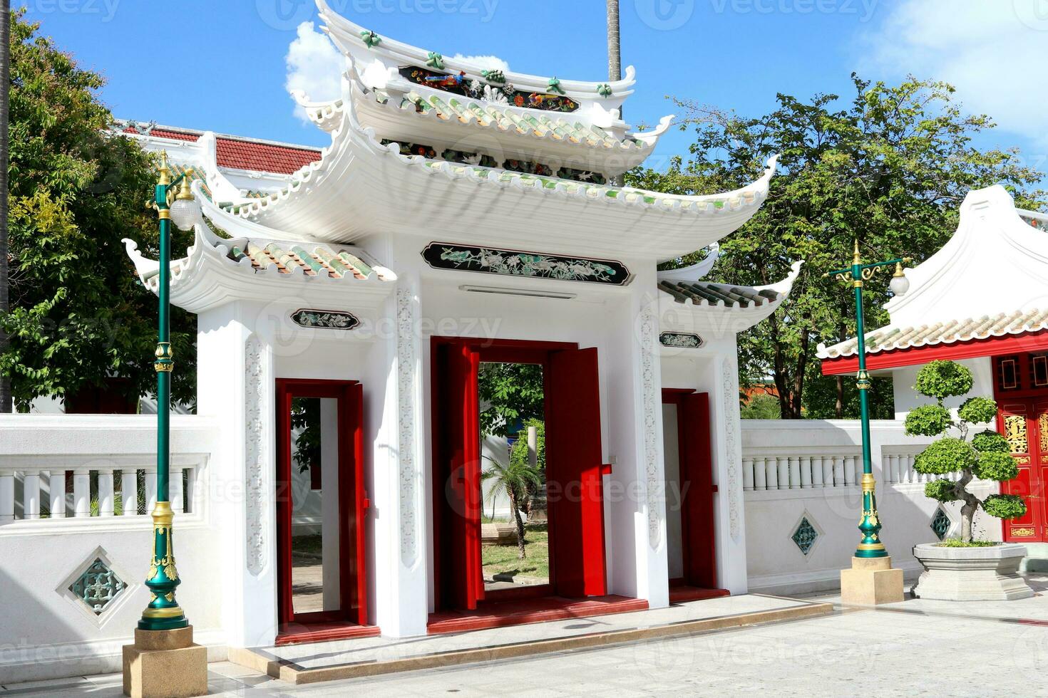 chino estilo de antiguo blanco puerta con techo, brillante rojo madera puerta y ligero azul cielo fondo, wat ratcha orasaram ratchaworawihan, tailandia foto