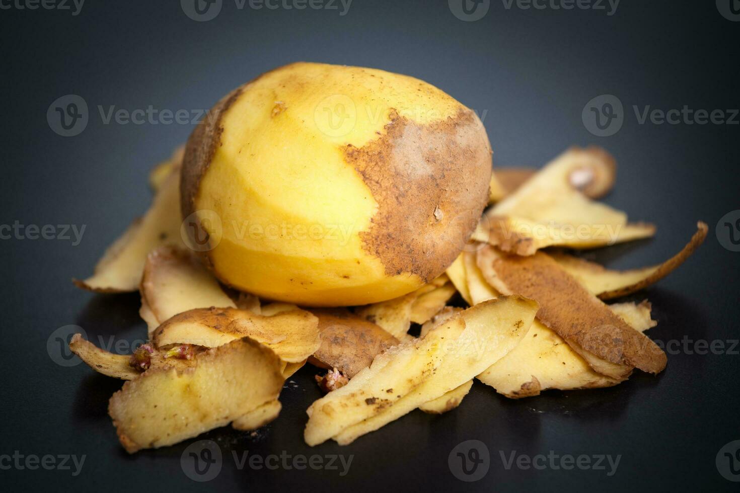 crudo pelado patatas y patata peladuras en negro antecedentes foto